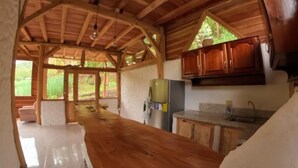 A rustic kitchen with wooden beams, a long wooden countertop, and wooden cabinets. - Eco-Finca Hostal Santorum (Vilcabamba)