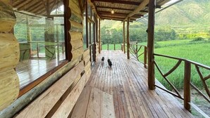 A wooden deck with benches and a hanging light fixture, overlooking a lush green landscape. - Eco-Finca Hostal Santorum (Vilcabamba)