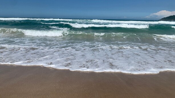 A beach with waves approaching the shore under a clear sky. - Refúgio na Praia do Campeche com Piscina (Florianópolis)
