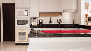 A modern kitchen with built-in appliances, a black countertop, and a red rug. - Refúgio na Praia do Campeche com Piscina (Florianópolis)