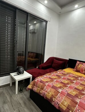Relax in a spacious bedroom with a large bed and a stylish nightstand, featuring a balcony view.