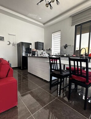 Enjoy cooking in this well-equipped kitchen with a sleek island, black refrigerator, oven, and microwave.