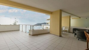 A spacious balcony with tiled flooring, a white railing, and a view of the sea. There are two white chairs and a small table. - Sea Sound Apartment (Sesimbra)