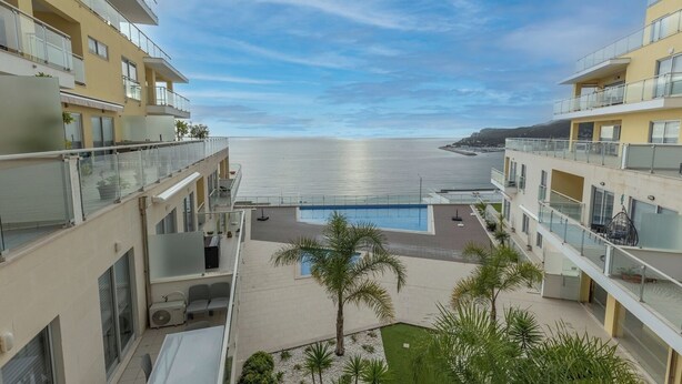 A modern apartment building with balconies overlooking a pool and the sea. - Sea Sound Apartment (Sesimbra)