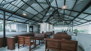 Un espace intérieur vaste, doté de hauts plafonds, de meubles en bois et de plantes en pot.
