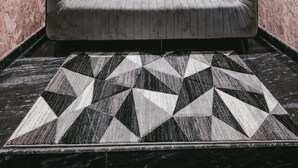 Un intérieur moderne avec un canapé gris, un tapis à motifs et un mur orné de l’inscription « FORTVIEW SUITES ».