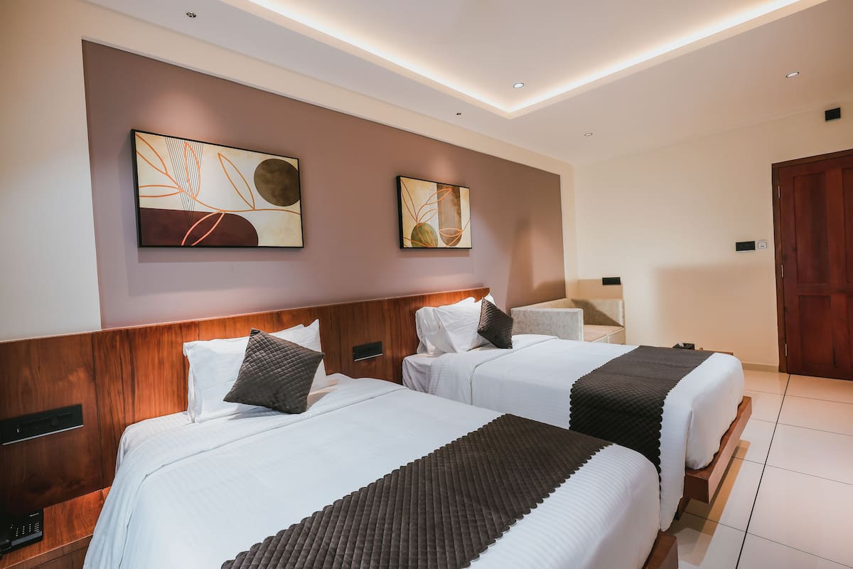 Habitación de hotel con dos camas y cabeceros de madera, además de un cuadro abstracto en la pared.