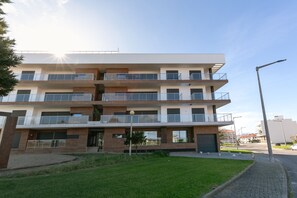 Een meerlaags woongebouw met balkons, een oprit en een verzorgd gazon.