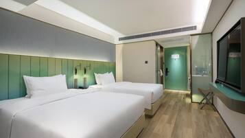 Een hotelkamer met twee bedden, een televisie en een badkamer zichtbaar door een deur.