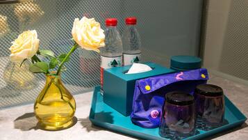 A bathroom vanity with a vase of white roses, a tissue box, and two bottles of hand sanitizer.