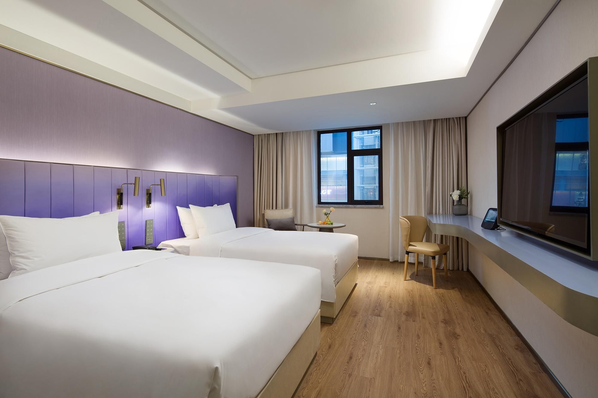 Habitación de hotel con dos camas, un escritorio, una silla, una ventana con vistas y un televisor de pantalla plana.