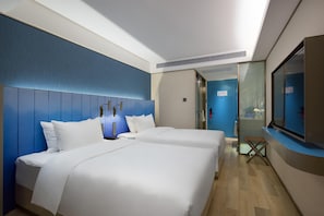 Habitación de hotel con dos camas, un televisor y un baño con ducha.
