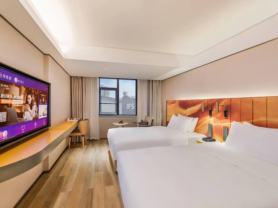 Habitación de hotel con dos camas, televisión, escritorio y ventana con vistas.