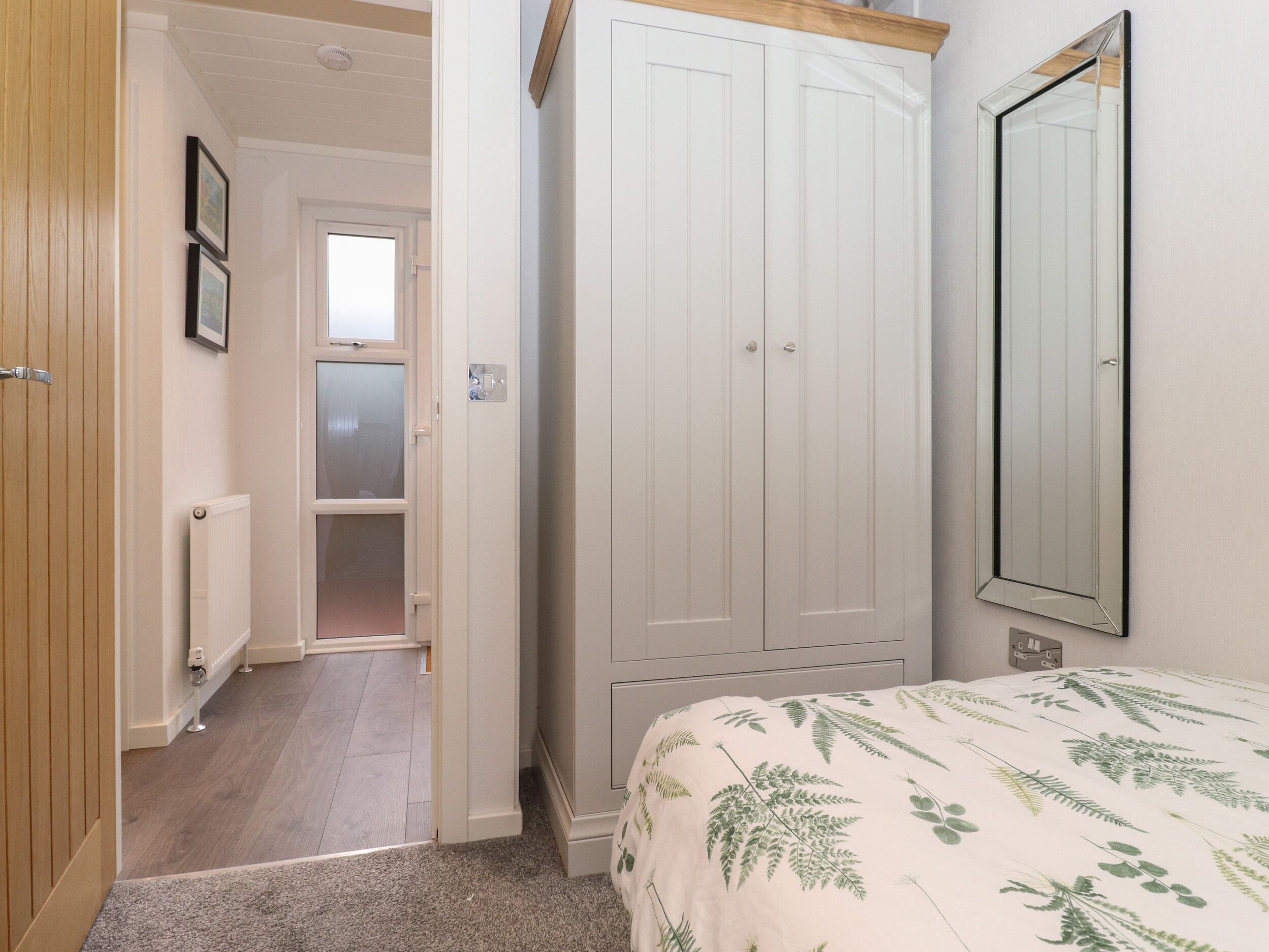 Un dormitorio con cama, armario, radiador y puerta que da a otra habitación.