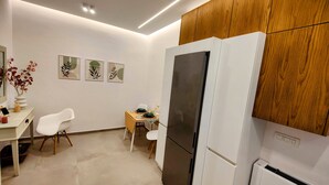 Une cuisine moderne avec des meubles blancs, un réfrigérateur noir et un mur recouvert de panneaux en bois.
