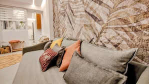 Un salon moderne avec un canapé gris, une tapisserie à motifs et une petite table d’appoint en bois.