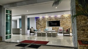 Um hall moderno com parede de pedra, televisão montada e áreas de estar.
