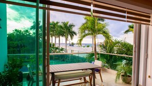 Uma varanda com mesa e cadeiras, com vista para uma piscina e palmeiras.