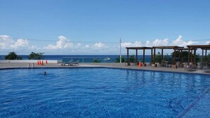 Piscina com espreguiçadeiras e área de estar coberta, com vista para um corpo de água.