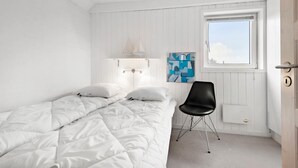 A bedroom with a bed, a chair, a window, and a wall-mounted light fixture. - Nice home in Fanø with WiFi (Fanø)