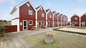 A row of red and white beach houses with picnic tables and a sandy area in the foreground. - Nice home in Fanø with WiFi (Fanø)