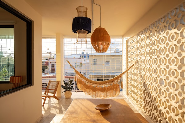 A room with a hammock, a wooden table, and a potted plant.