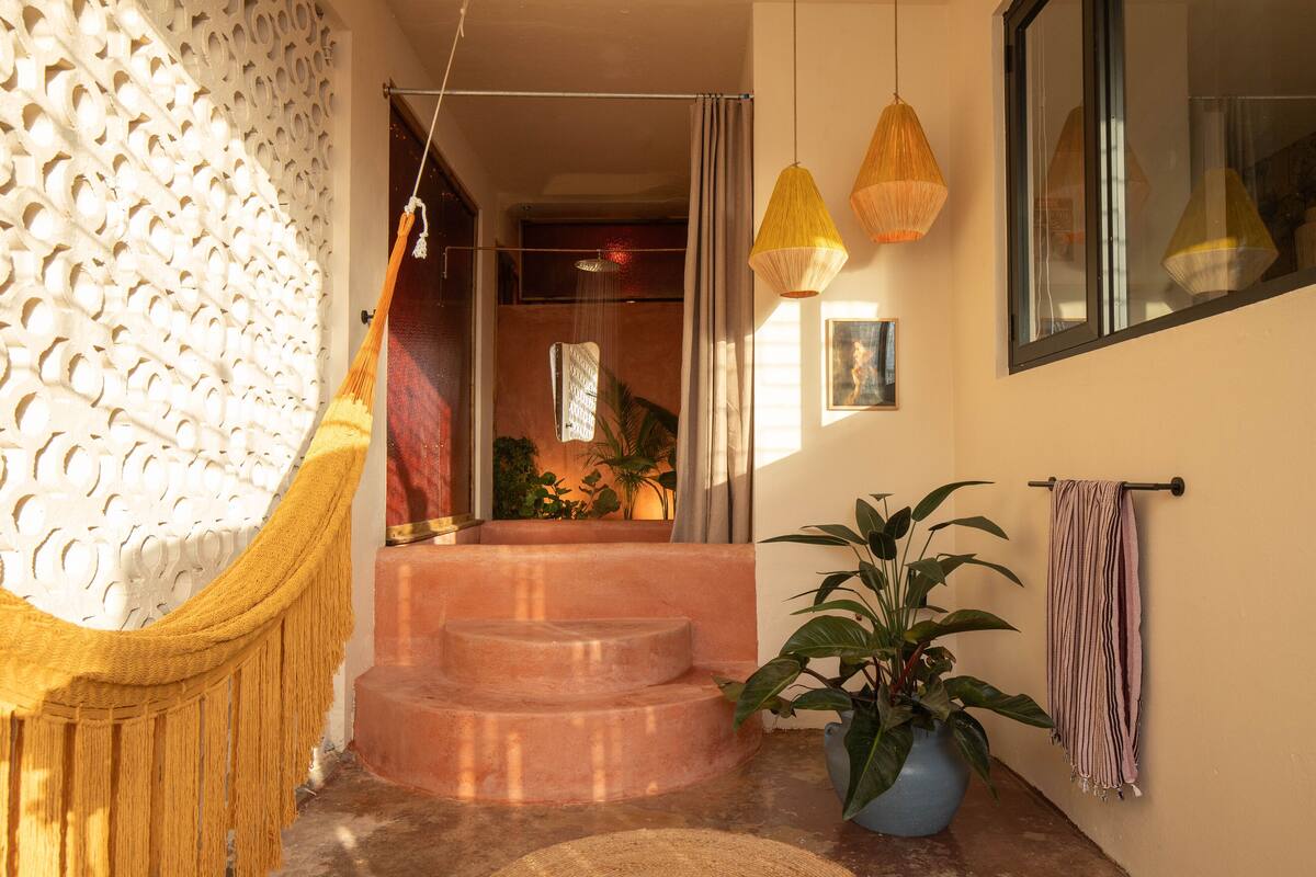 A room with a hammock, a staircase, a potted plant, and a hanging light fixture.