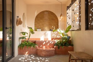 A modern interior with a stone archway, a seating area with plants, and a hanging light fixture. - NOA by DW (San Juan)