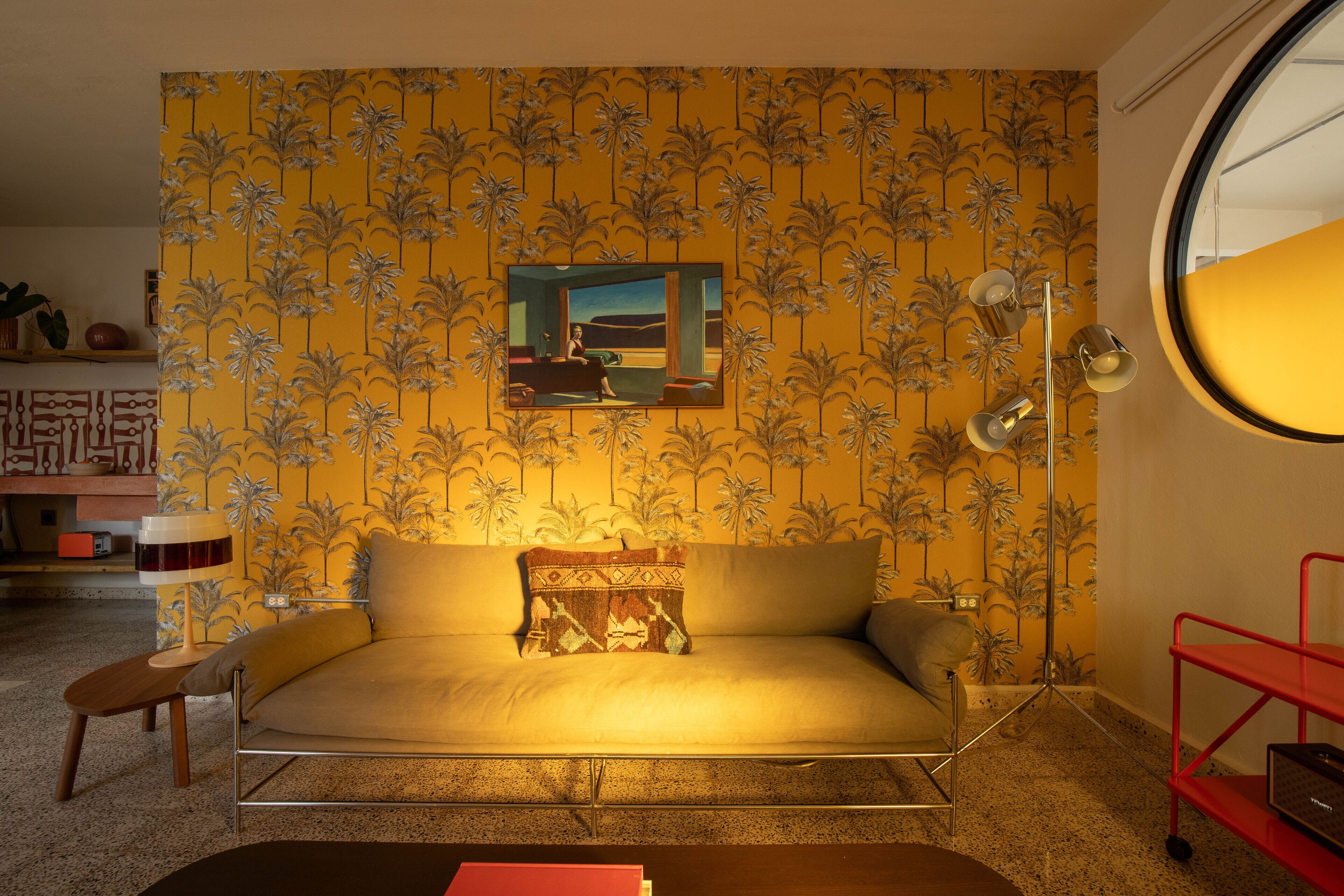A room with a sofa, a lamp, a small table, and a red shelf.