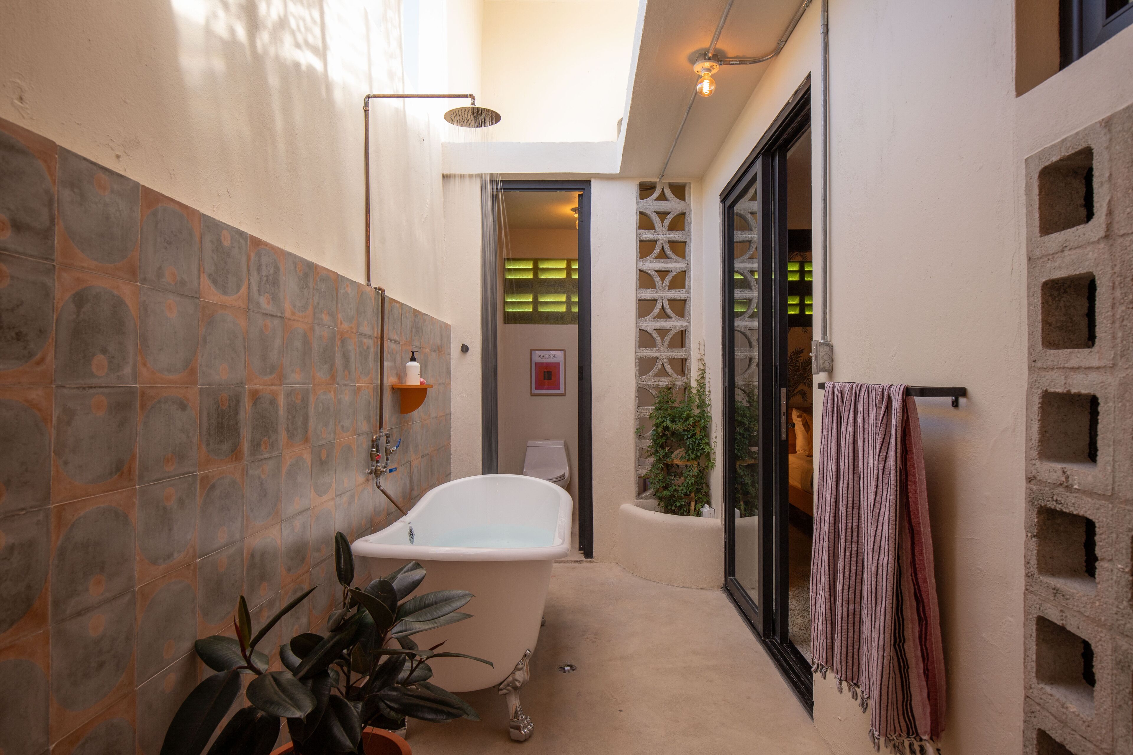 A narrow bathroom with a freestanding bathtub, a showerhead, and a towel rack.