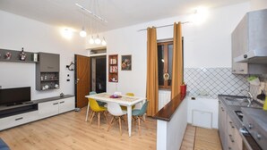 Una cocina moderna con comedor, piso de madera y televisor.