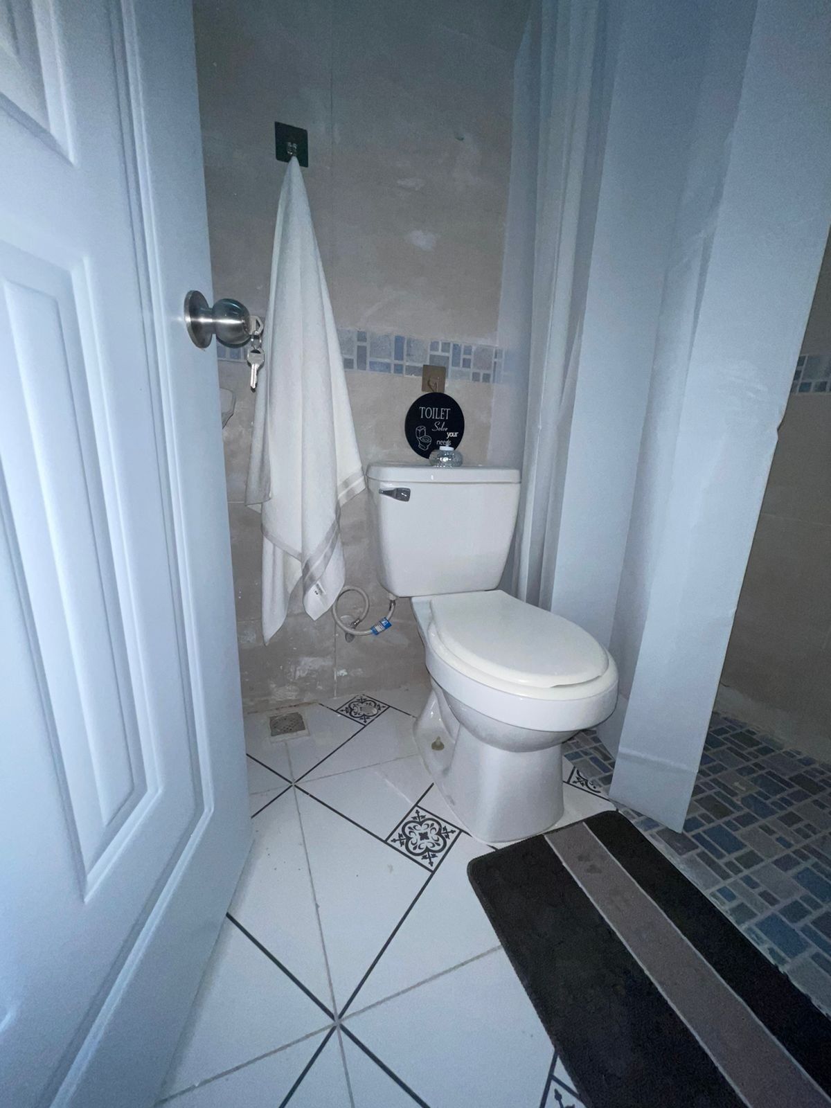 Een badkamer met een toilet, een handdoek aan de muur en een betegelde vloer.