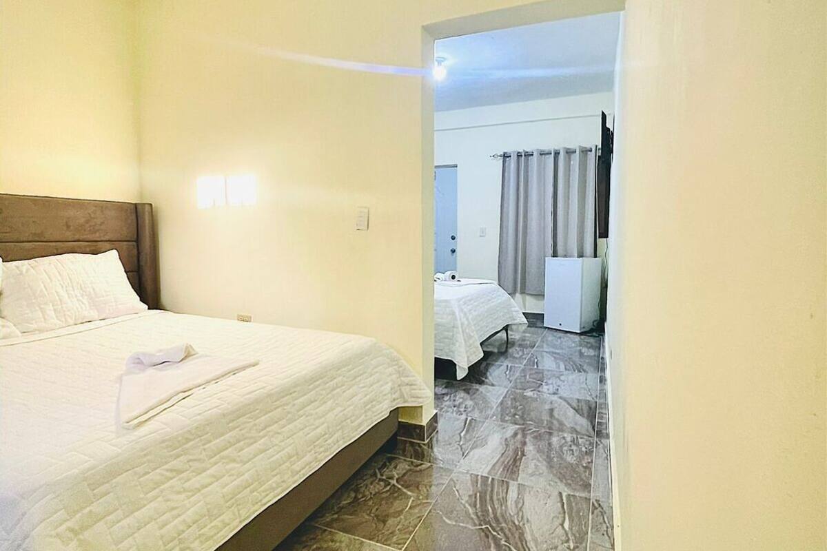 A hotel room with a bed, a nightstand, and a bathroom visible through an open door.