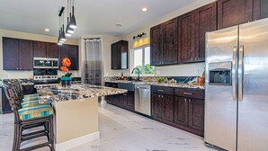A modern kitchen with dark wood cabinets, stainless steel appliances, and a marble island. - Hilo Town Center home (Hilo)