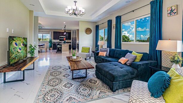 A spacious living room with a modern sofa, a dining area, and a kitchen in the background. - Hilo Town Center home (Hilo)