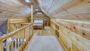 A wooden cabin with a loft bedroom, a small bathroom, and a staircase.