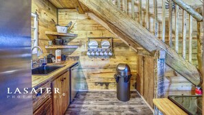 A rustic kitchen with wooden walls, a sink, and a stove.
