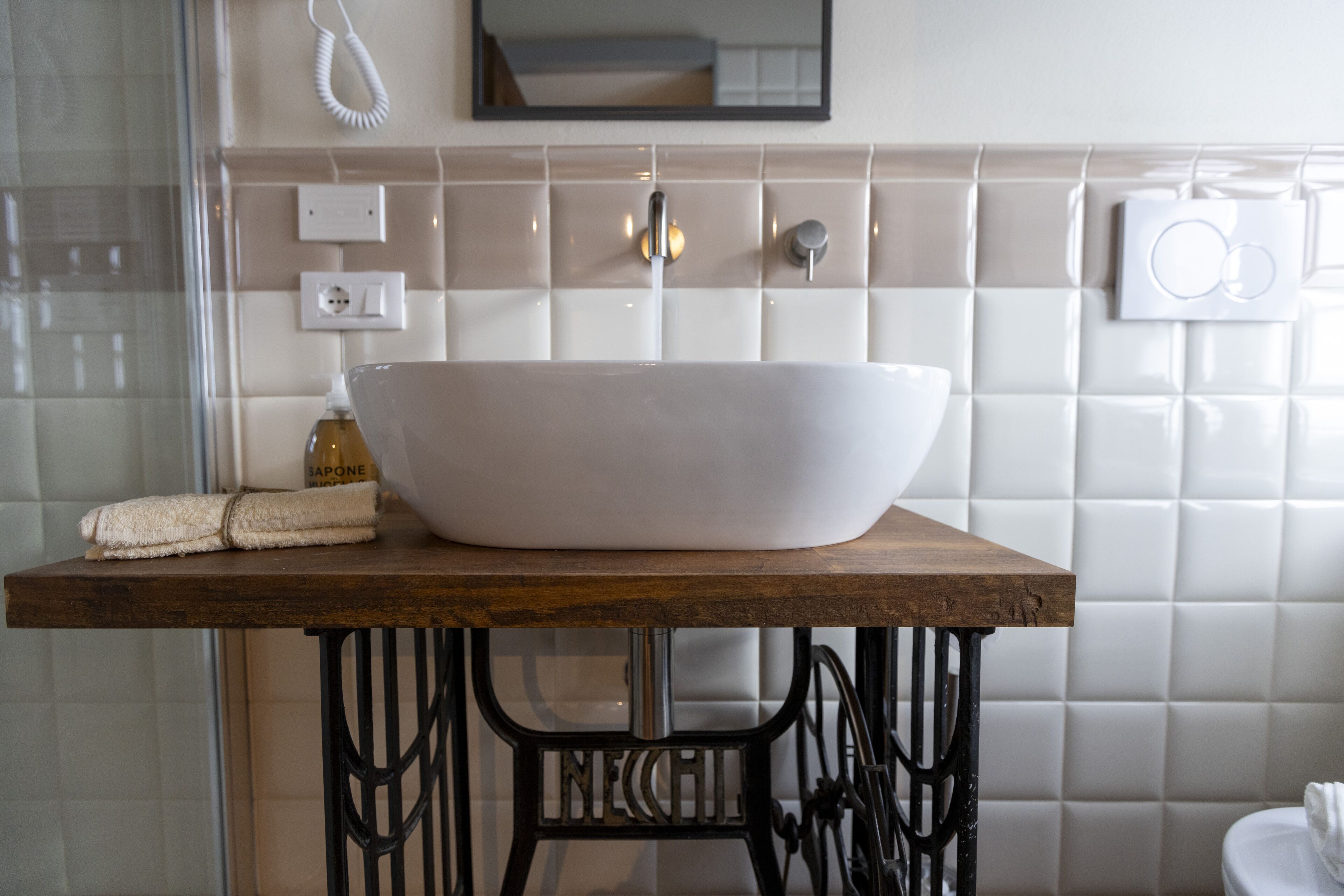 A bathroom with a large white vessel sink on a wooden countertop, a mirror above, and a towel on the counter.