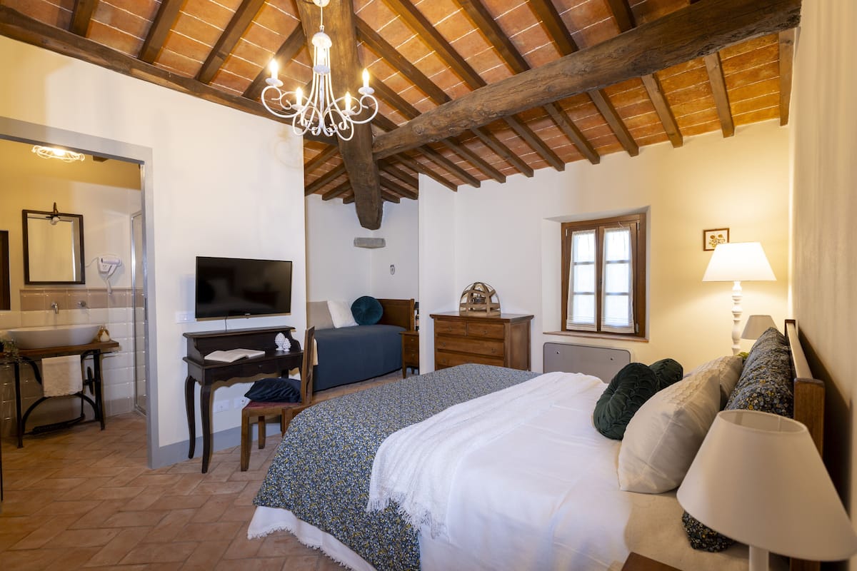 A bedroom with a bed, bedside table, lamp, and a TV.