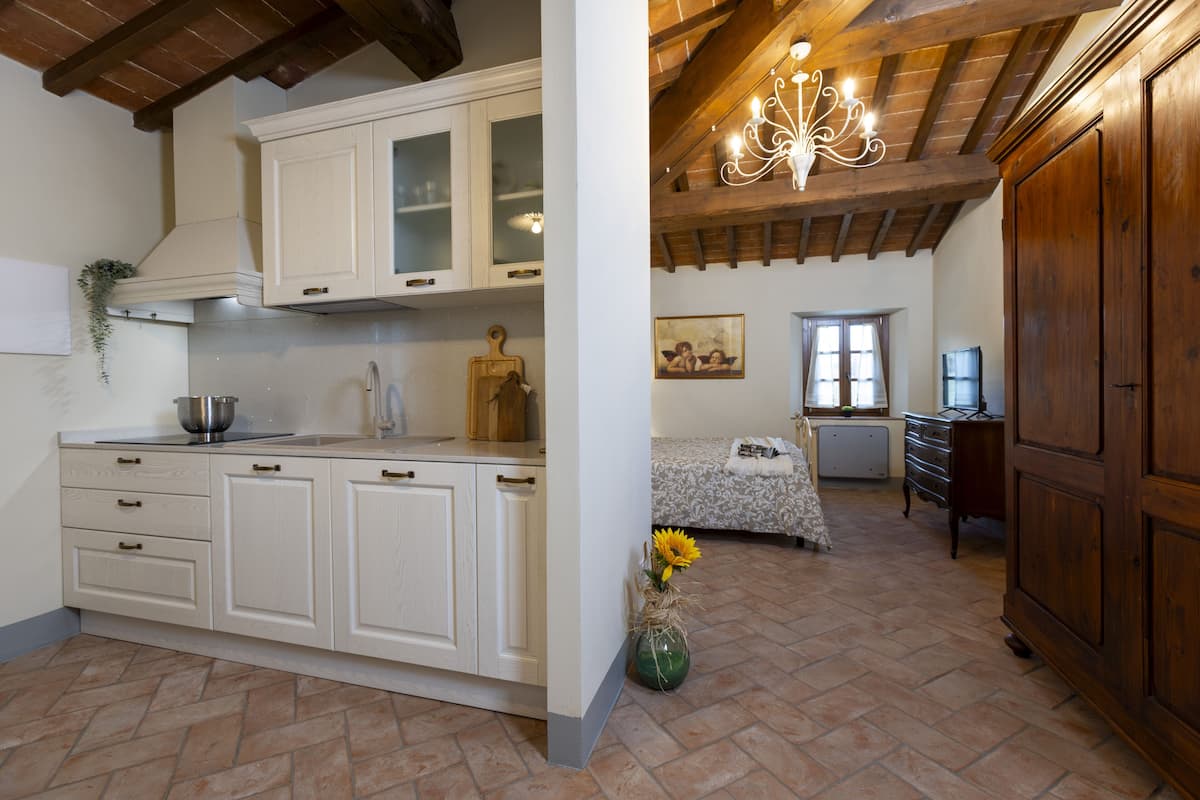 A kitchen with white cabinets, a wooden ceiling, and a chandelier.