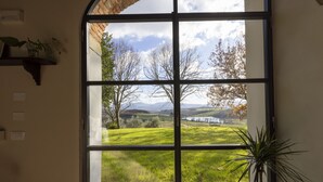 A room with a large window offering a view of a grassy landscape and trees.