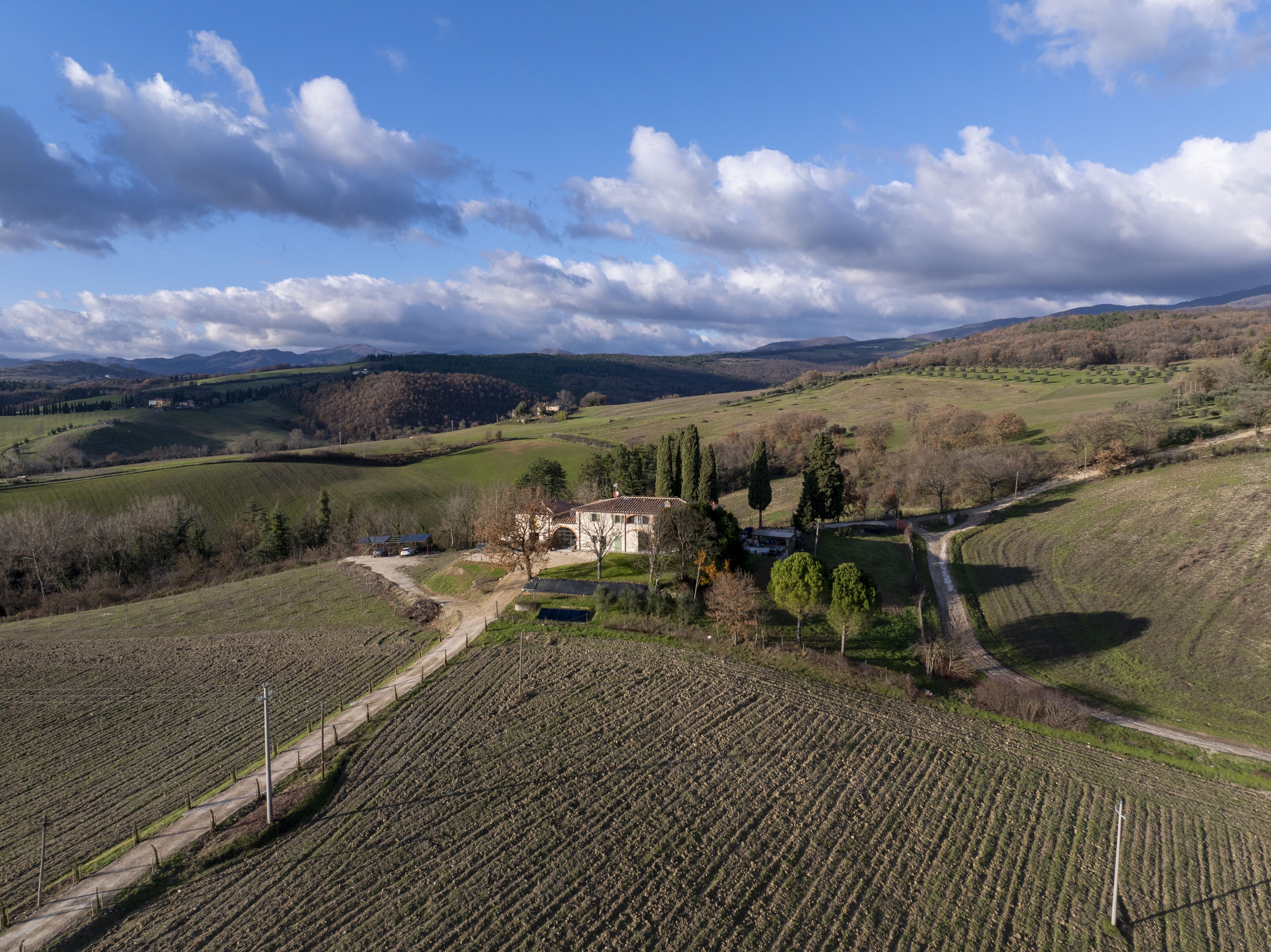 Un paysage rural avec des champs en terrasses, un petit bâtiment et des collines douces en arrière-plan.