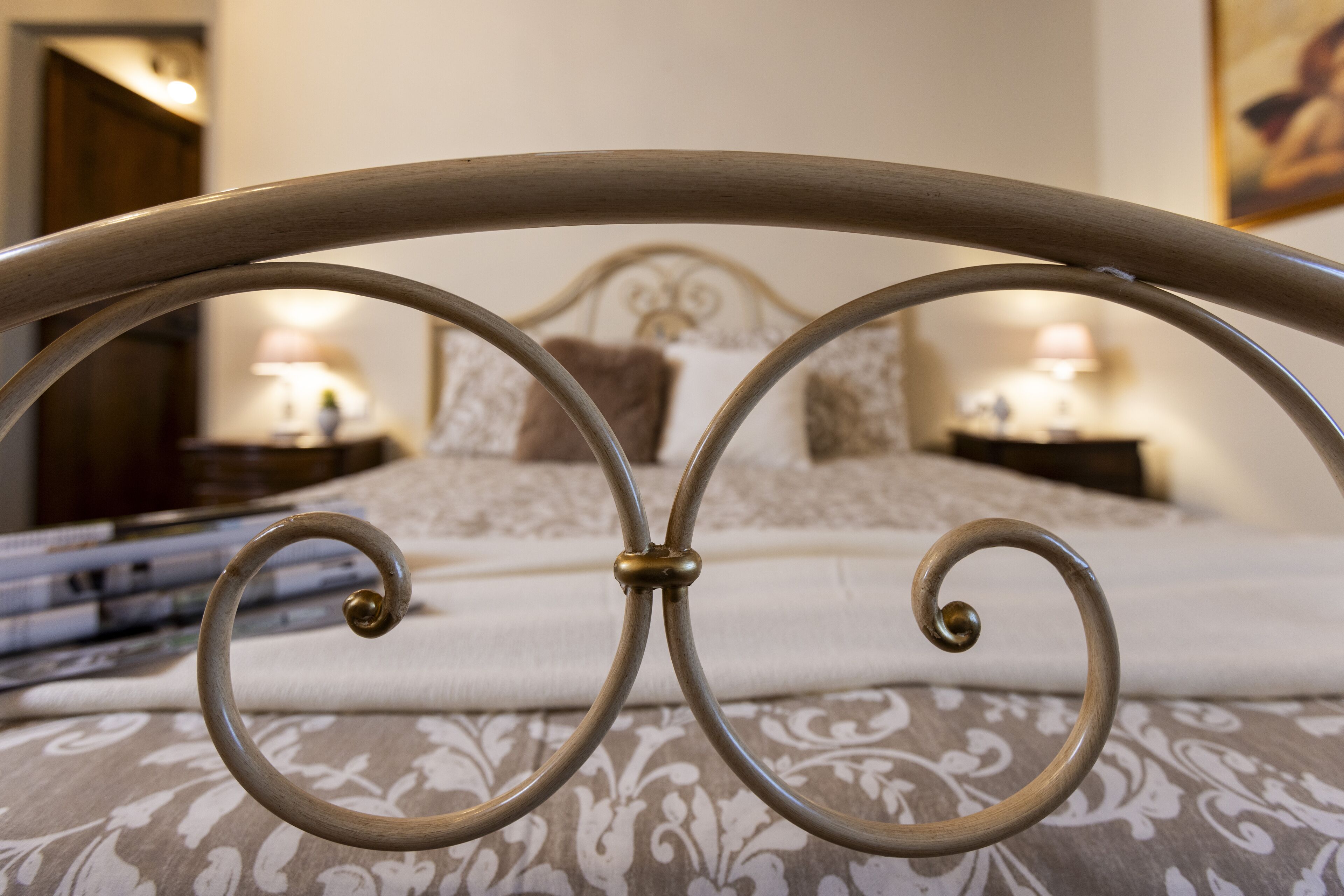 A bed with a metal headboard, a patterned bedspread, and two bedside lamps.