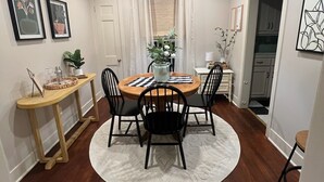 A dining room with a round table, black chairs, a wooden side table, and a white rug. - Charming Pine Cottage near SFA, azalea gardens,  & walking trails. (Nacogdoches)
