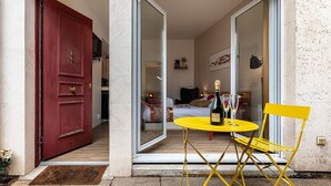 A room with a bed, a table with a bottle and glasses, and a chair. - Havre de Paix  Jacuzzi (Asnieres-sur-Seine)