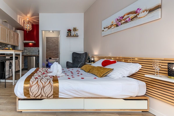 A modern bedroom with a bed, bedside table, and a small seating area. - Havre de Paix Jacuzzi (Asnieres-sur-Seine)