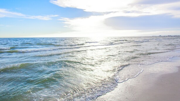 Ein Strand mit Wellen und blauem Himmel.