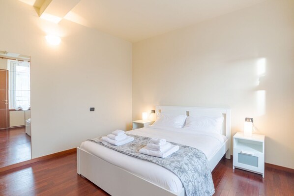 Une chambre d’hôtel avec un grand lit, des tables de chevet, un miroir et une vue sur la salle de bain.