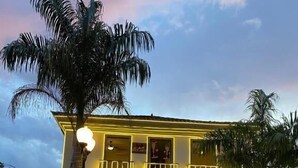 A building with a balcony and a palm tree in front. - Pousada Relicário (Tiradentes)