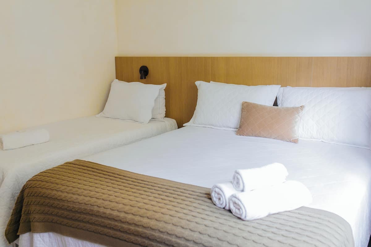 A hotel room with a large bed, two pillows, a headboard, and a brown blanket.
